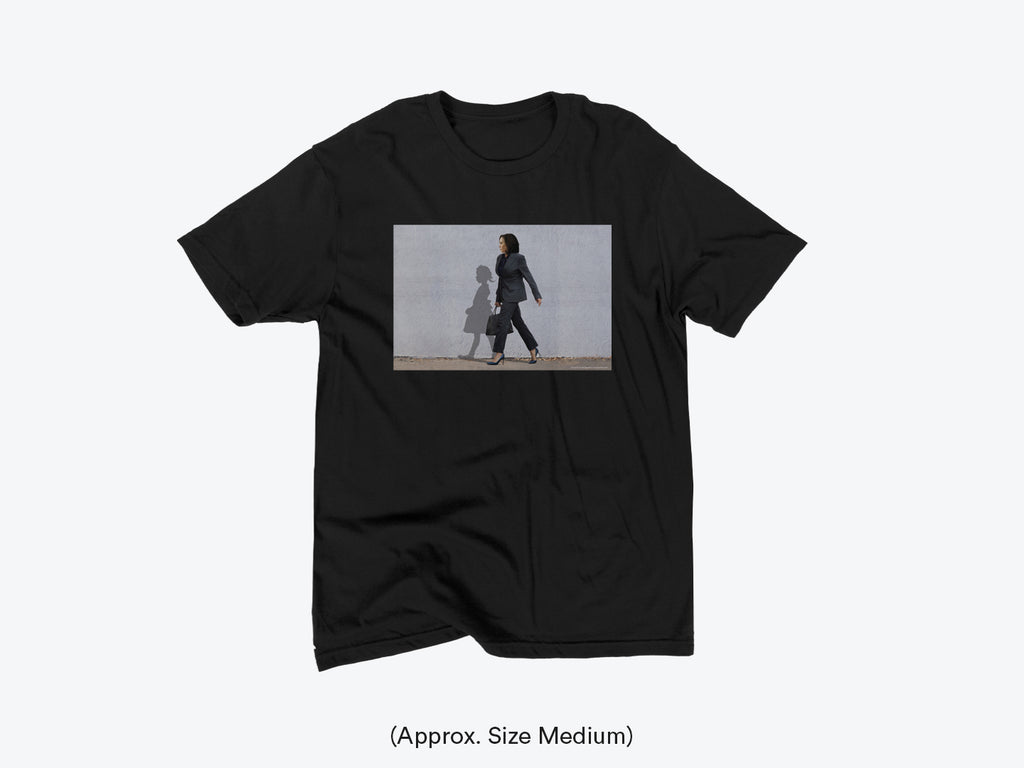Black crew neck t-shirt with a print of Harris Kamala and a shadow of a little girl walking on the front.